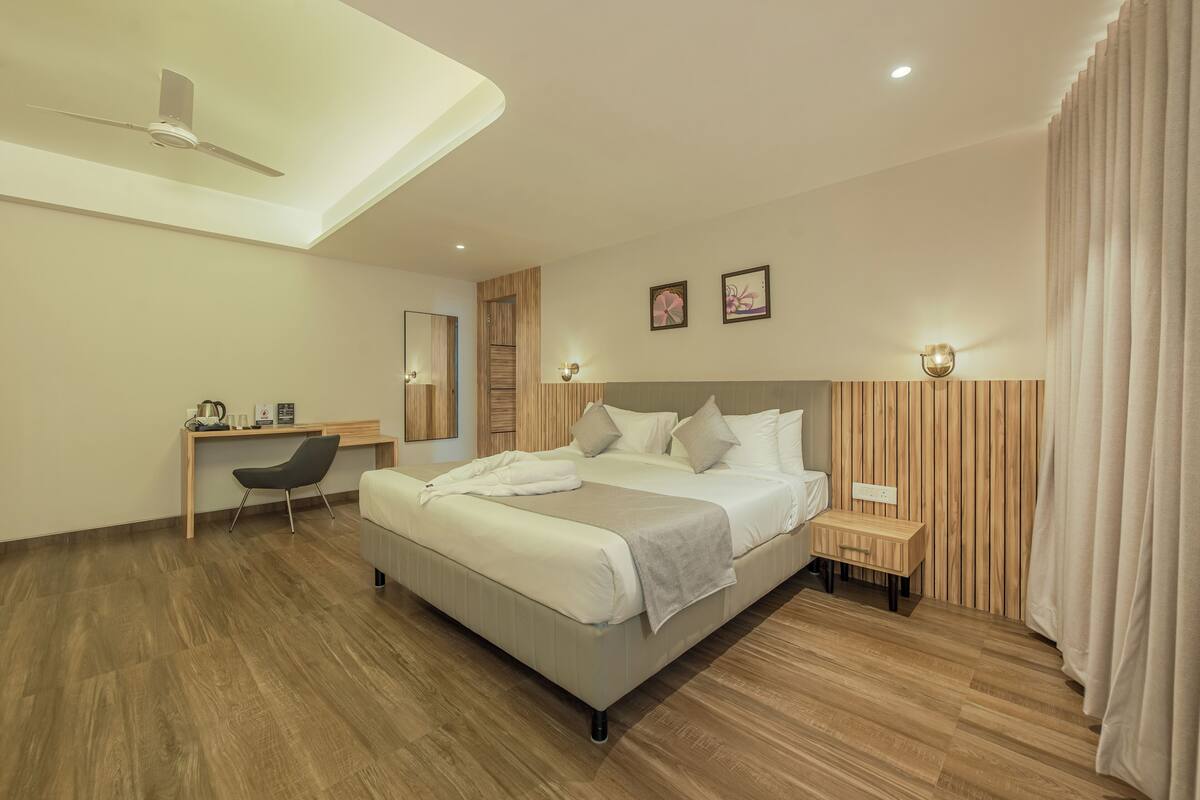 A modern hotel room with a large bed, a desk, and a chair.