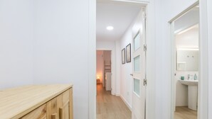 Ein Flur mit Holzausbau, einer weißen Tür und einem Badezimmer mit Waschbecken und Spiegel.