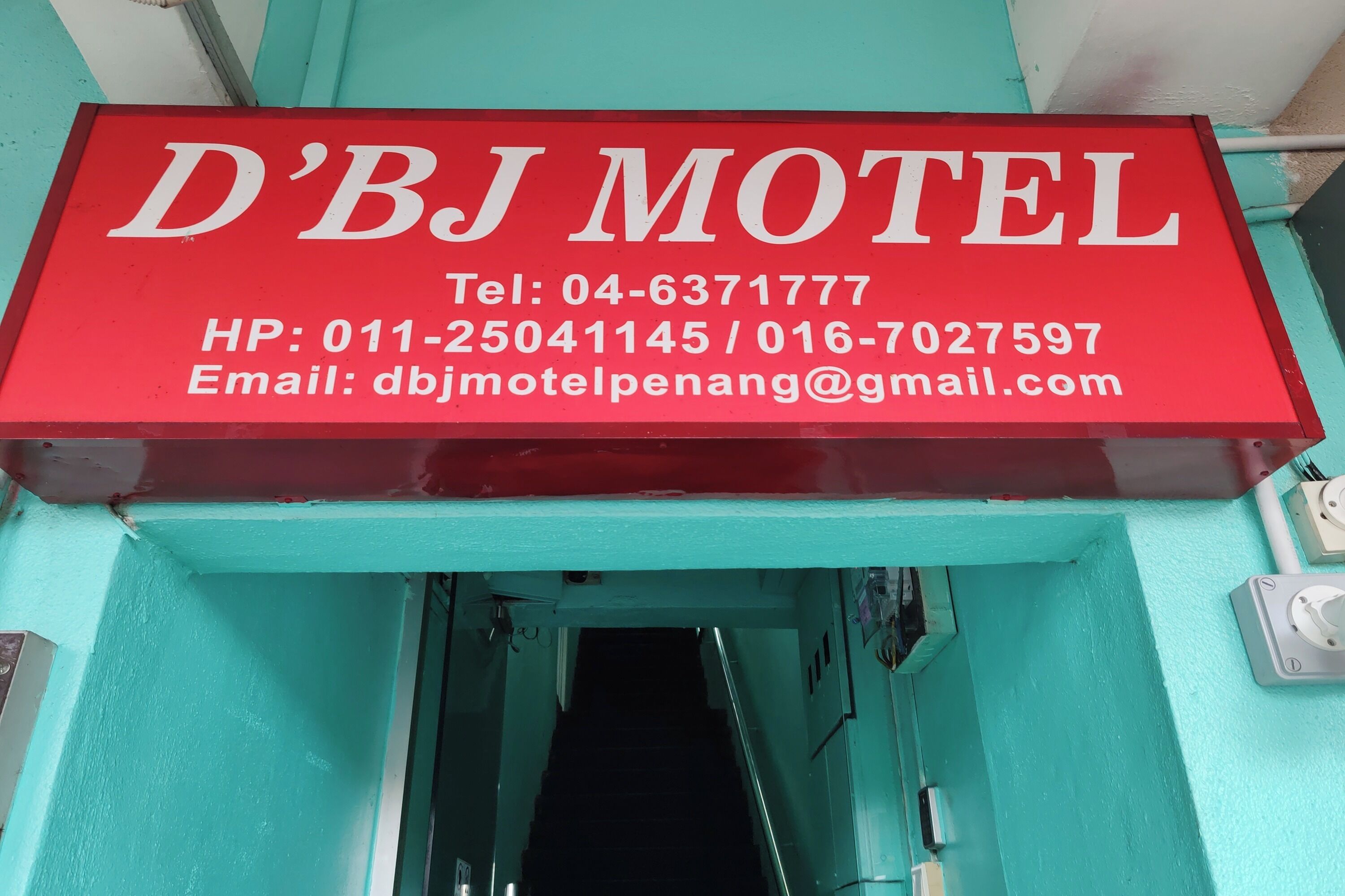 Señal roja del motel D'BJ con información de contacto.