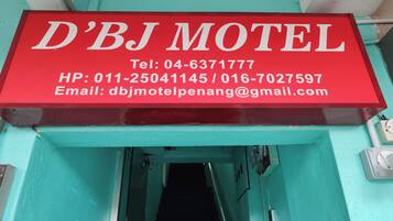 Señal roja del motel D'BJ con información de contacto.