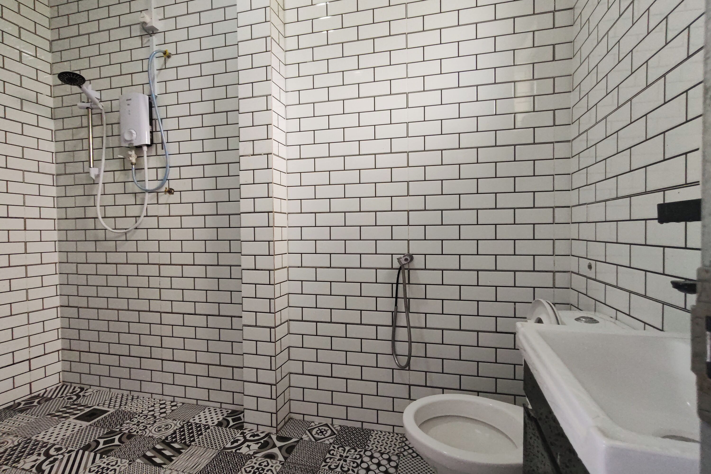 Un baño con paredes de azulejos blancos, ducha, inodoro y bañera.