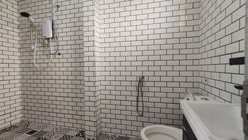 Un baño con paredes de azulejos blancos, ducha, inodoro y bañera.