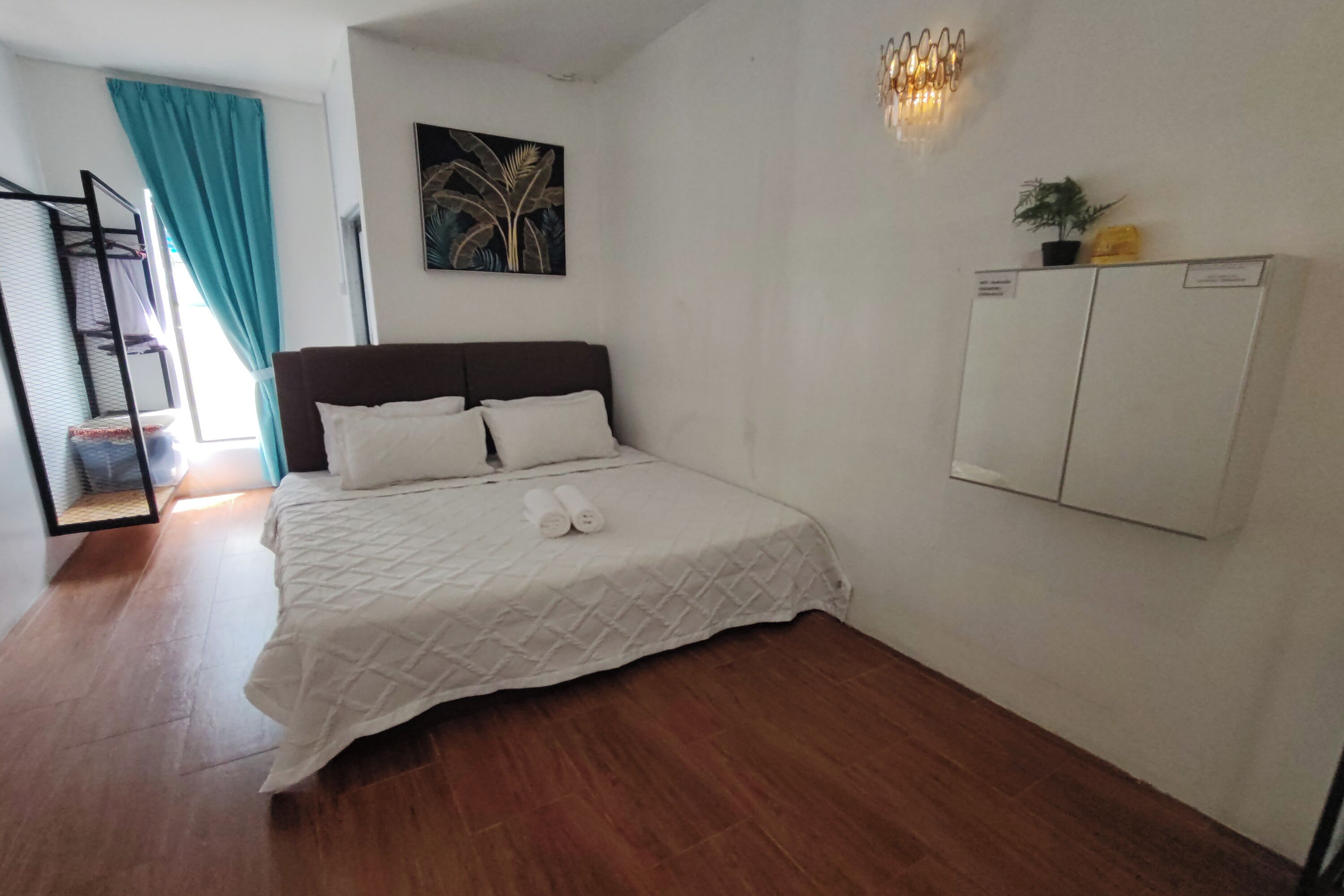 Un dormitorio con cama, armario, un cuadro y una planta en maceta.