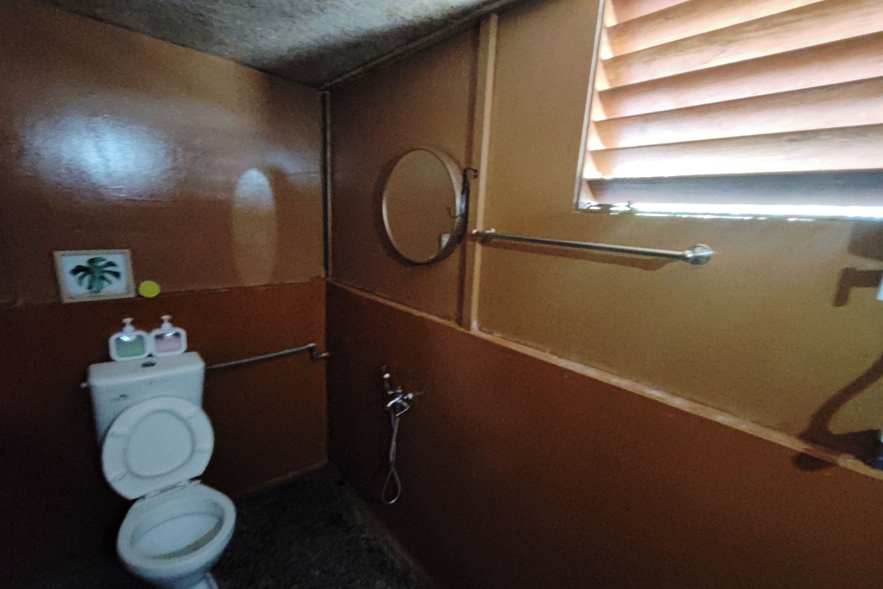 A small, compact bathroom with a toilet, a hand dryer, and a mirror.