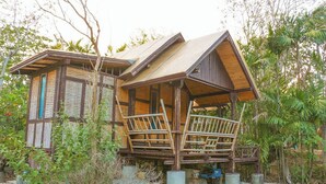 Un chalet rustique en bois, doté d’un toit en pente et entouré d’une végétation luxuriante.