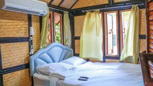 Une chambre avec un lit, une fenêtre avec des rideaux, un climatiseur et un téléphone fixé au mur.