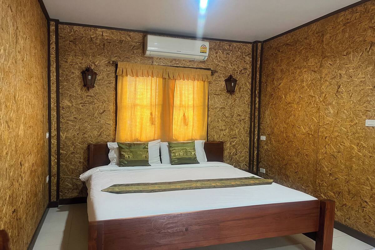 A bedroom with a wooden bed, yellow curtains, and an air conditioning unit on the wall.