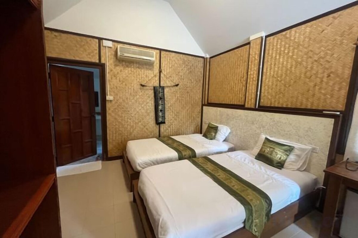 A hotel room with two beds, a wooden door, an air conditioning unit, and a textured wall.