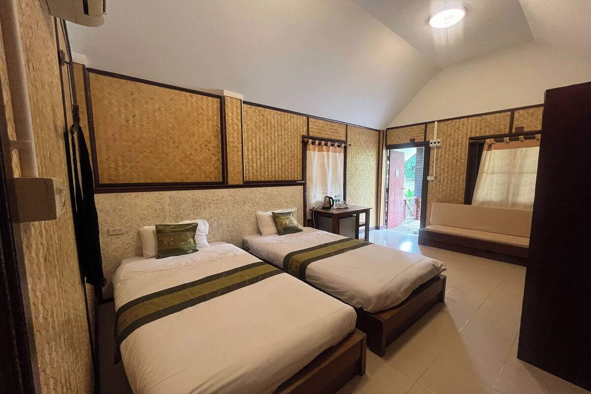 A hotel room with two beds, a small table, and a sofa.