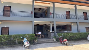 A two-story building with a balcony, a staircase leading to the entrance, and a parked scooter. - Namkhem Inn (Takua Pa)