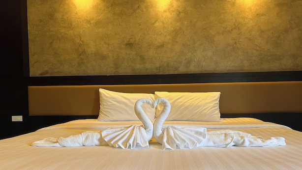 A hotel room with a large bed, two pillows, and a wall-mounted light fixture. - Namkhem Inn (Takua Pa)