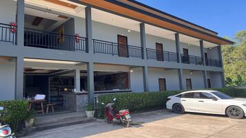 Un edificio de varios pisos con balcones, una entrada cubierta y un coche blanco estacionado.