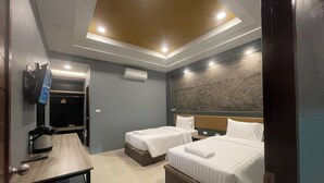 A hotel room with two beds, a desk, a TV, and a ceiling light. - Namkhem Inn 2 (Takua Pa)