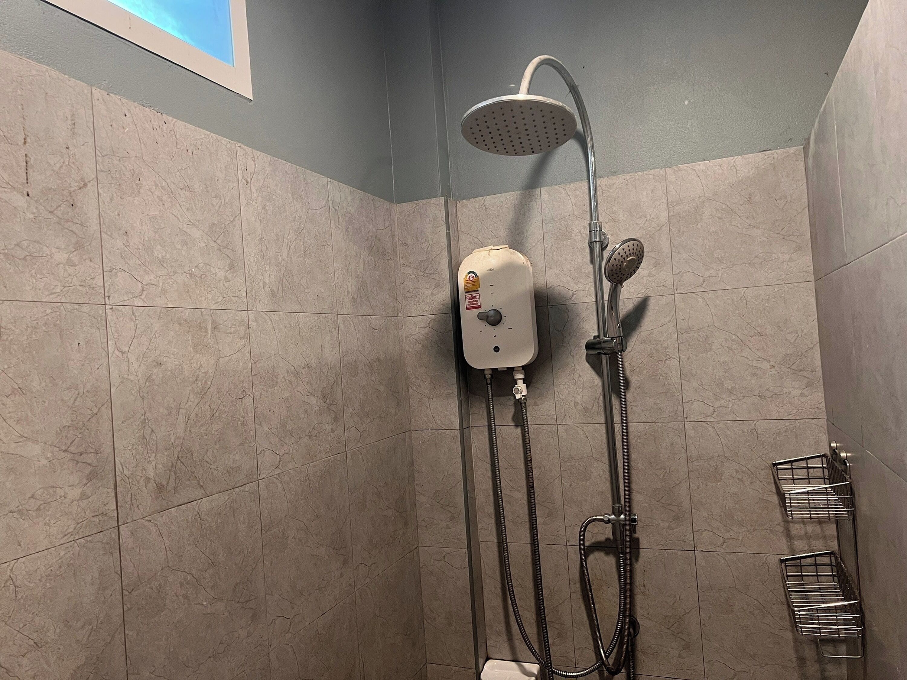 A shower area with a handheld showerhead, a wall-mounted faucet, and a handheld showerhead.