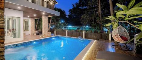 A modern house with a swimming pool, a balcony, and a wooden deck.