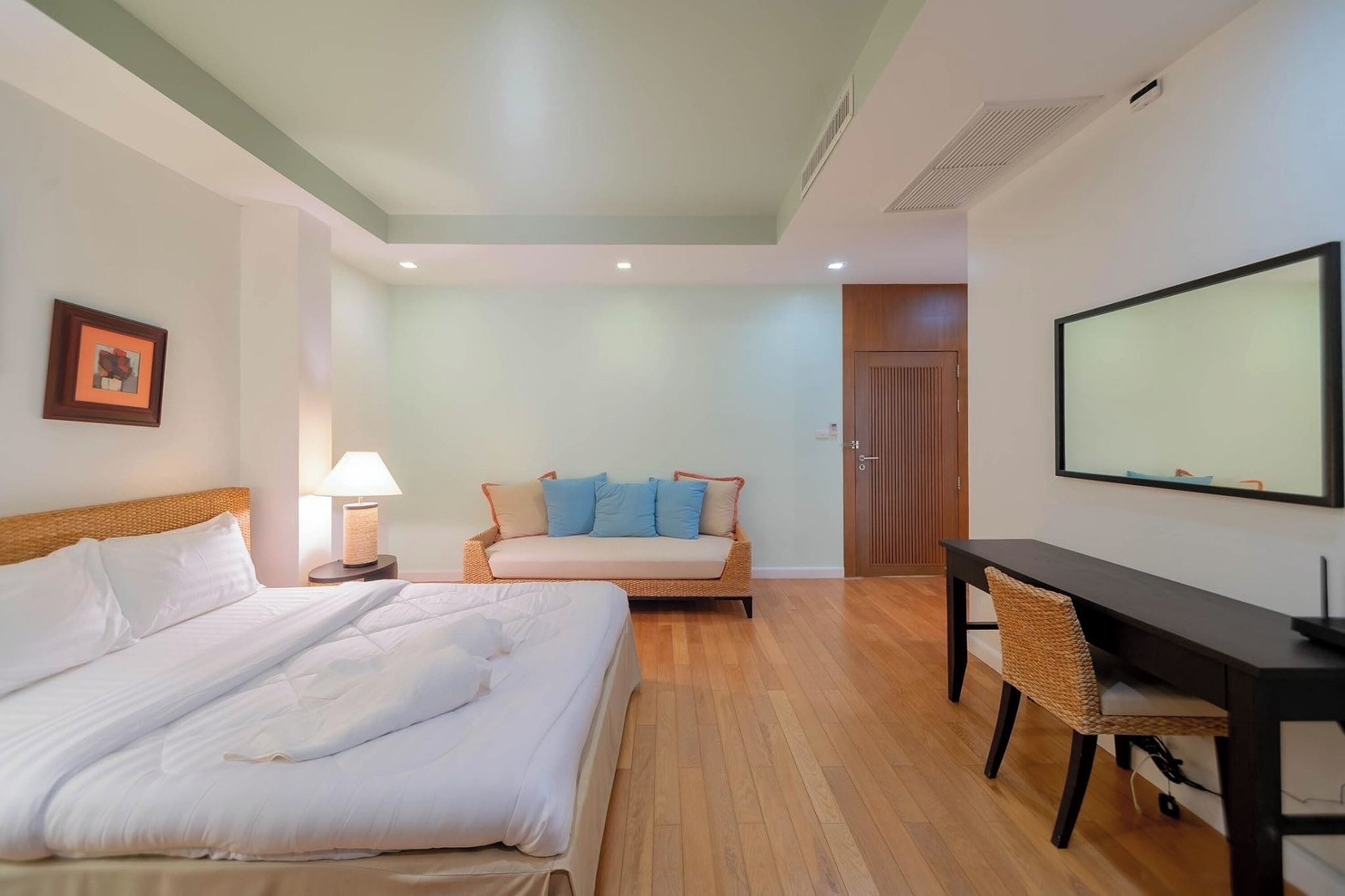 A hotel room with a large bed, a sofa, a desk, and a television.