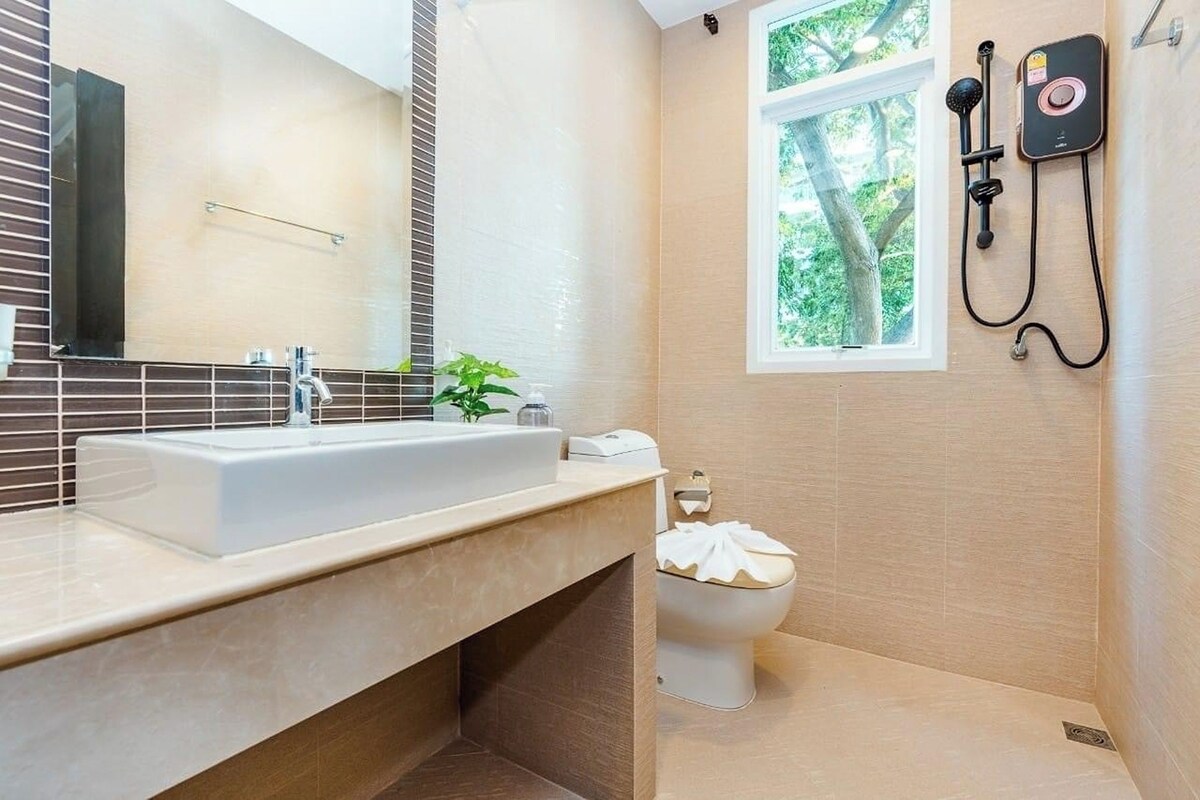 A modern bathroom with a large sink, a toilet, and a shower area.