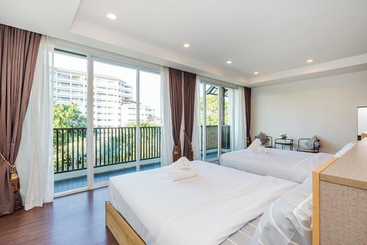 A hotel room with two beds, a balcony, and a view of buildings.