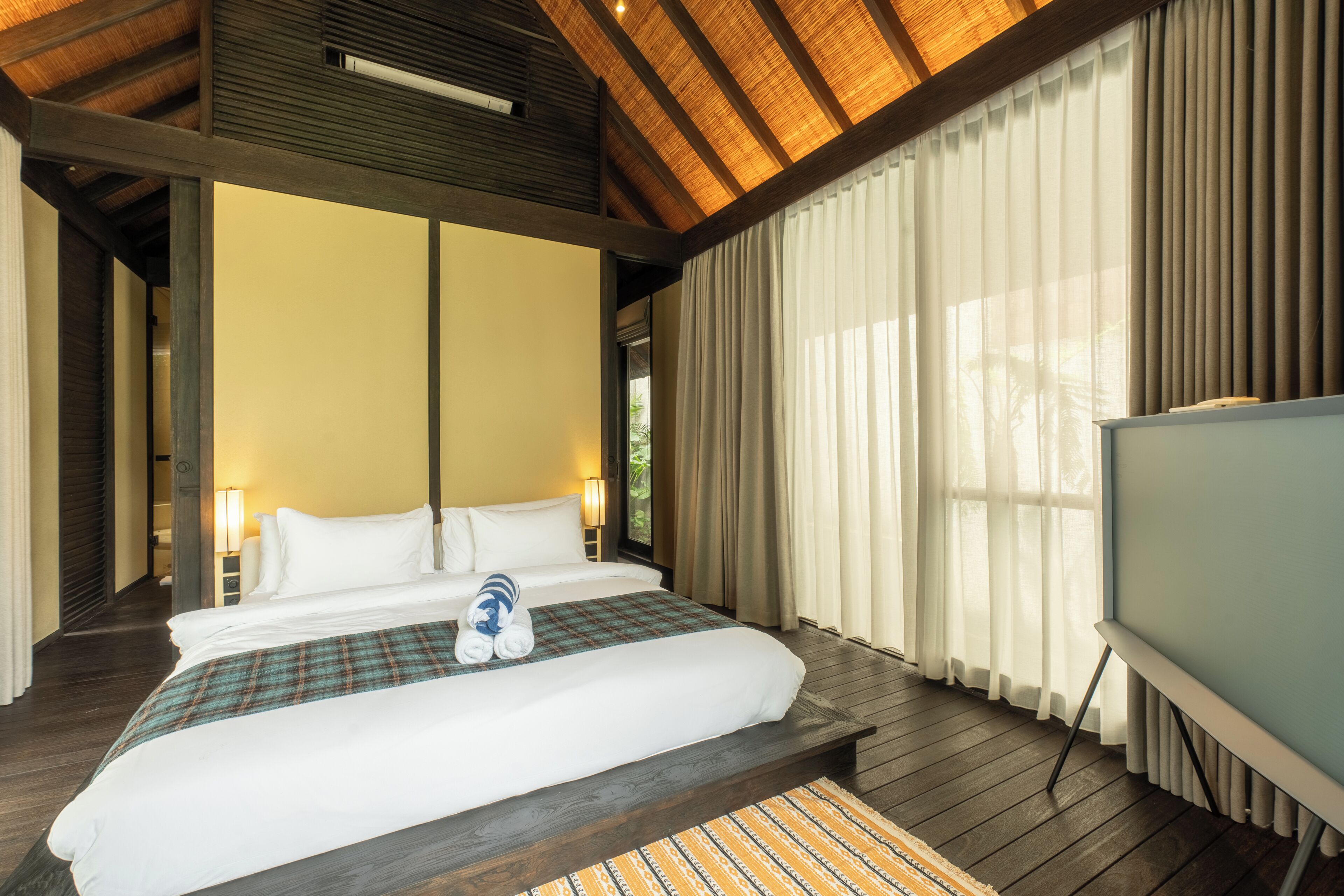 Een hotelkamer met een groot bed, een televisie en uitzicht op de omgeving.
