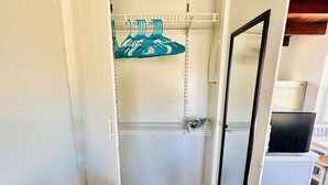 A walk-in closet with open doors, a wooden floor, and a red table in the foreground. - Cottage 33: Pineapple Place - Waterfront Lodging in Downtown Tavares, FL (Tavares)