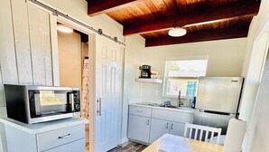 A compact kitchen with a microwave, a coffee maker, and a refrigerator. - Cottage 33: Pineapple Place - Waterfront Lodging in Downtown Tavares, FL (Tavares)