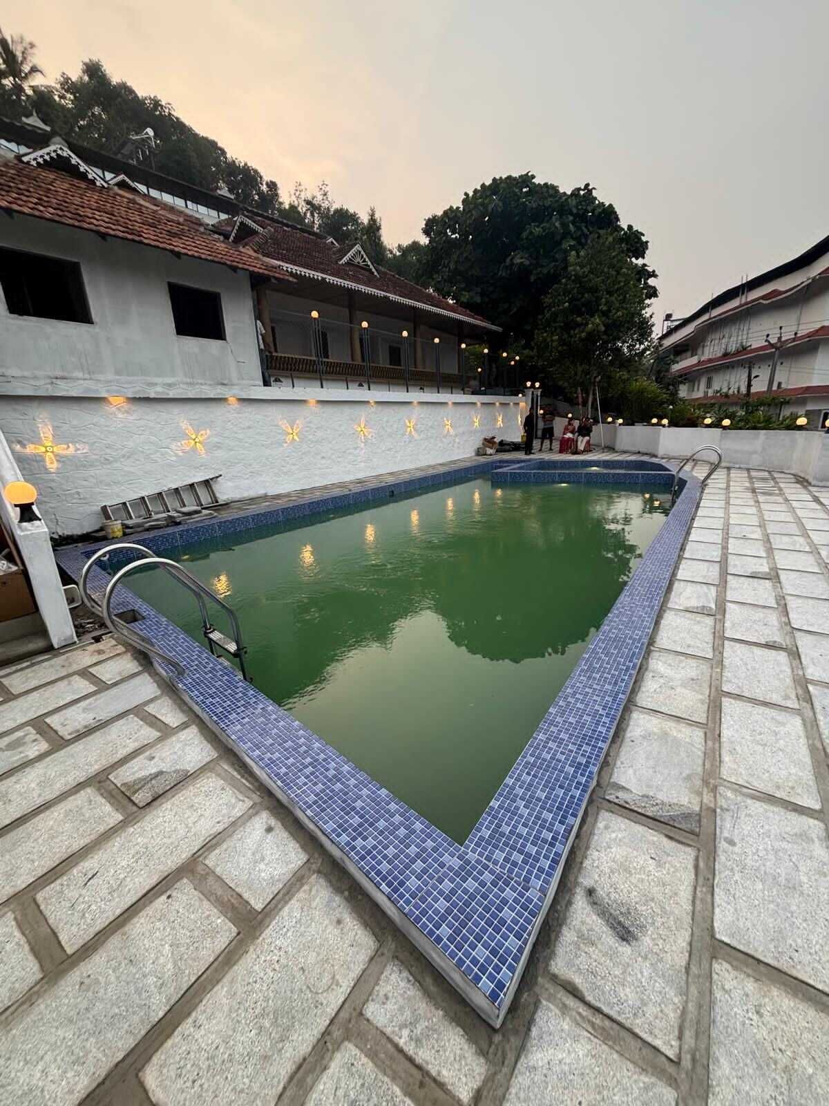 A rectangular swimming pool with a tiled edge, surrounded by a stone deck.