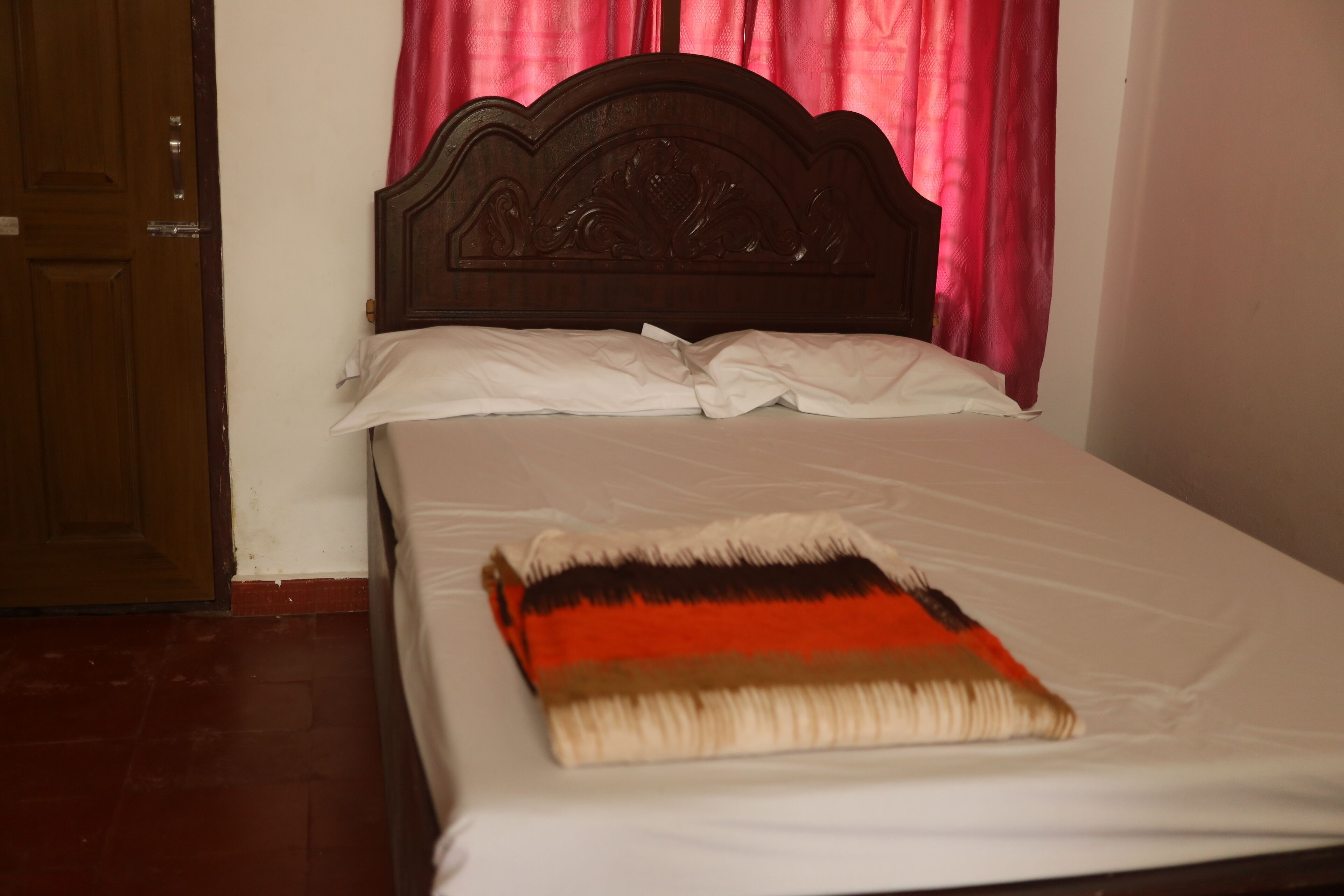 Una cama con cabecera de madera, ropa de cama blanca y una manta con estampado.