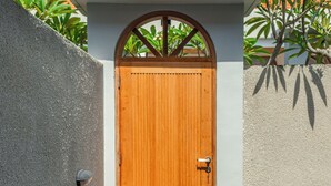 A wooden door with a white wall and a concrete wall beside it. - Comoda Seminyak (Seminyak)
