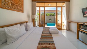 A hotel room with a large bed, a TV, and a view of a pool and garden. - Comoda Seminyak (Seminyak)