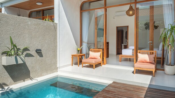 A modern outdoor pool area with wooden deck, lounge chairs, and a glass-enclosed living space. - Comoda Seminyak (Seminyak)