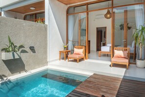 Un espace piscine extérieur moderne, doté d’une terrasse en bois, de chaises longues et d’un espace de vie clos par des baies vitrées.
