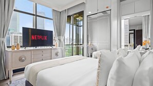 Une chambre d’hôtel moderne avec un grand lit, un téléviseur posé sur une commode et une vue sur la ville.