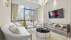 Un salon moderne doté d’une grande fenêtre, de canapés blancs, d’une table basse et d’un téléviseur affichant le logo « NETFLIX ».