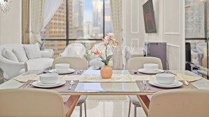 Un espace repas moderne avec une table en verre, des assiettes blanches et un vase de fleurs.