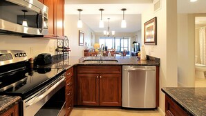 A modern kitchen with stainless steel appliances, wooden cabinets, and a central island with a sink.