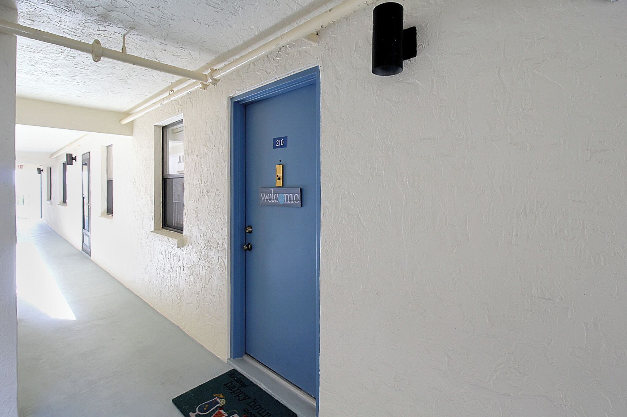 Ein Flur mit einer blauen Tür, auf der „210“ steht, und einem Schild mit der Aufschrift „Willkommen.“