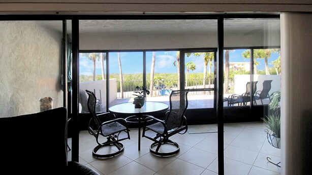 A room with a large sliding glass door leading to an outdoor patio with a round table and four chairs.