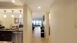 A modern kitchen with stainless steel appliances, pendant lighting, and a view into the dining area.