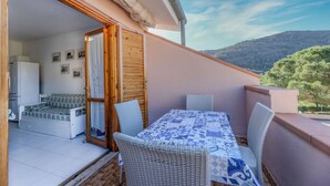 A balcony with a table and chairs, a sofa, and a refrigerator. - Cala Rossa 40 Pool & Relax (Rio dell'Elba)