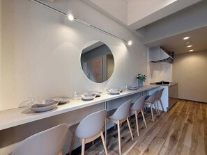 A modern kitchen with a central island, a round mirror, and a seating area with chairs.