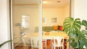 A dining area with a wooden table and white chairs, a green sofa, and a potted plant. - The Maple Flat: high end 2-bedroom apartment in Blairsville (Blairsville)