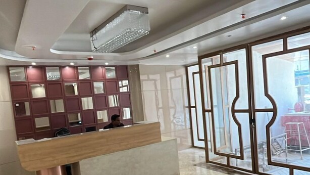 A modern lobby with a marble floor, a reception desk, and a large glass door leading outside. - Nirvana Bliss (Prayagraj)