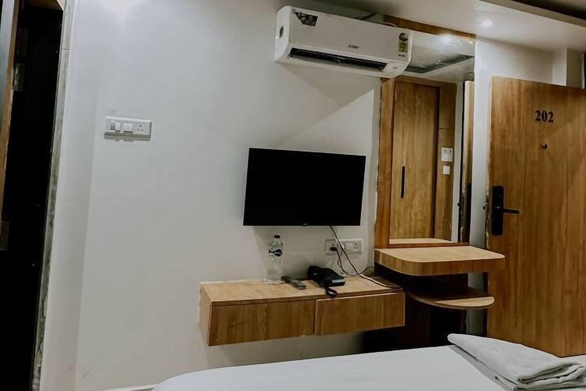 Habitación de hotel con cama, escritorio, computadora, televisor de pantalla plana y armario de madera.