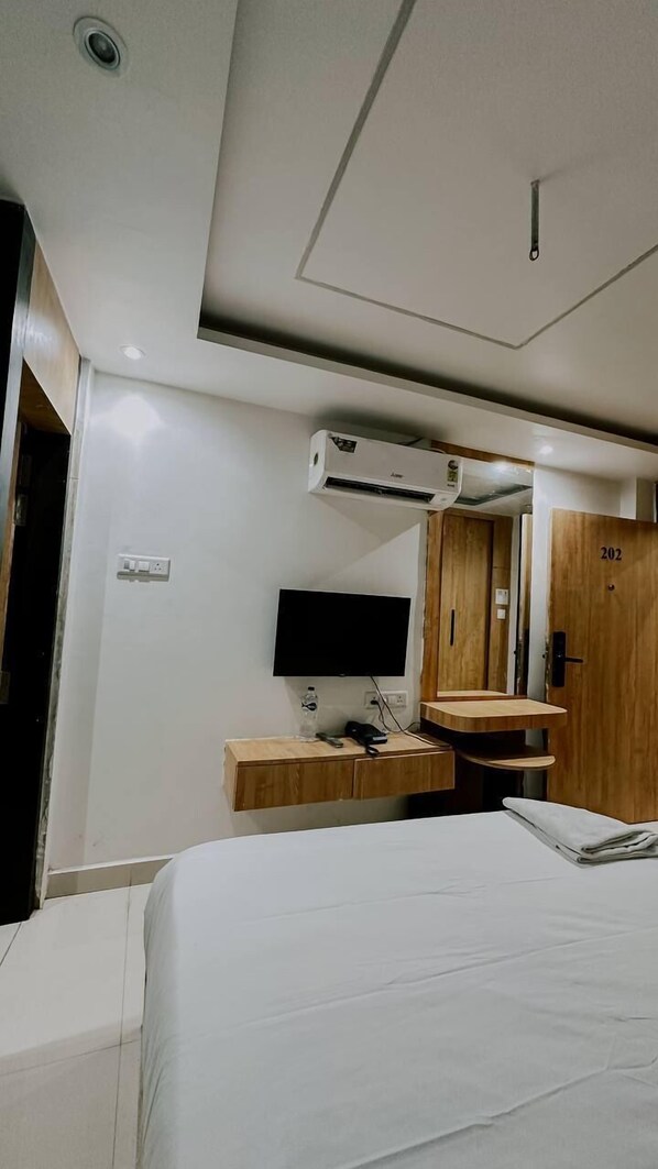 Ein Hotelzimmer mit einem Bett, einem Schreibtisch mit Computer, einem Flachbildfernseher und einem Holzschrank.