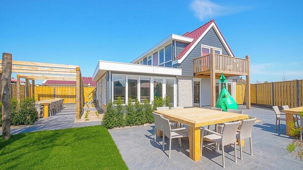 A modern house with a large patio, outdoor furniture, and a wooden deck. - Callantsoog Group Getaway Beach (Callantsoog)