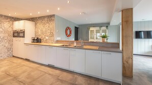 A modern kitchen with a central island, built-in appliances, and a large window. - Callantsoog Group Getaway Beach (Callantsoog)