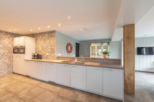 Una cocina moderna con una isla central, electrodomésticos integrados y un ventanal grande.
