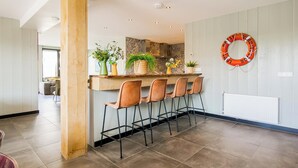 A modern kitchen with a central island, bar stools, and a life ring on the wall. - Callantsoog Group Getaway Beach (Callantsoog)