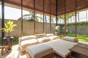 A spacious bedroom with a large bed, a wooden table, and a view of palm trees.