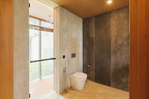 A modern bathroom with a toilet, shower, and a large window.